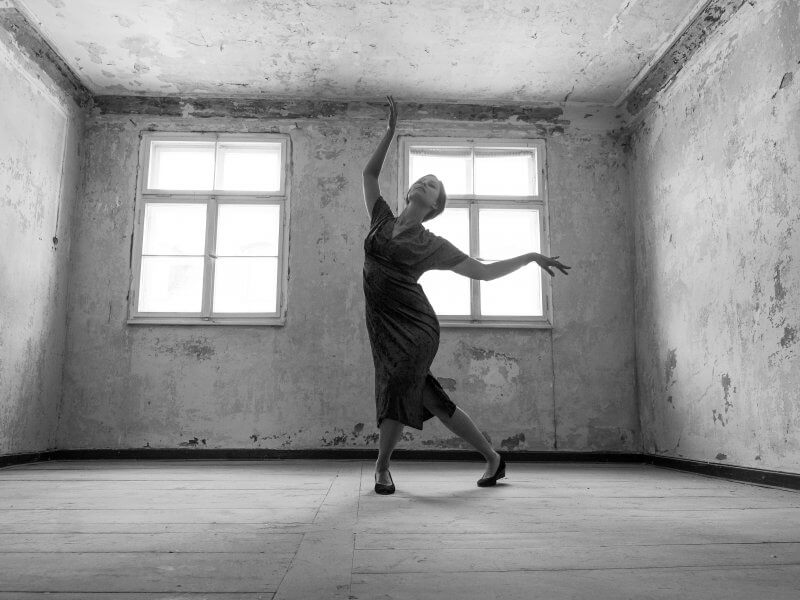 Das Model und Schauspielerin Anna Mariani nimmt eine tanzende Form ein und steht in einem alten leeren Raum.