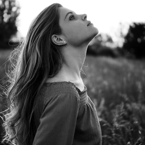 Lilli Schmidt in einer schwarz-weiss Aufnahme. Sie steht in einem Feld und sieht in die Luft.