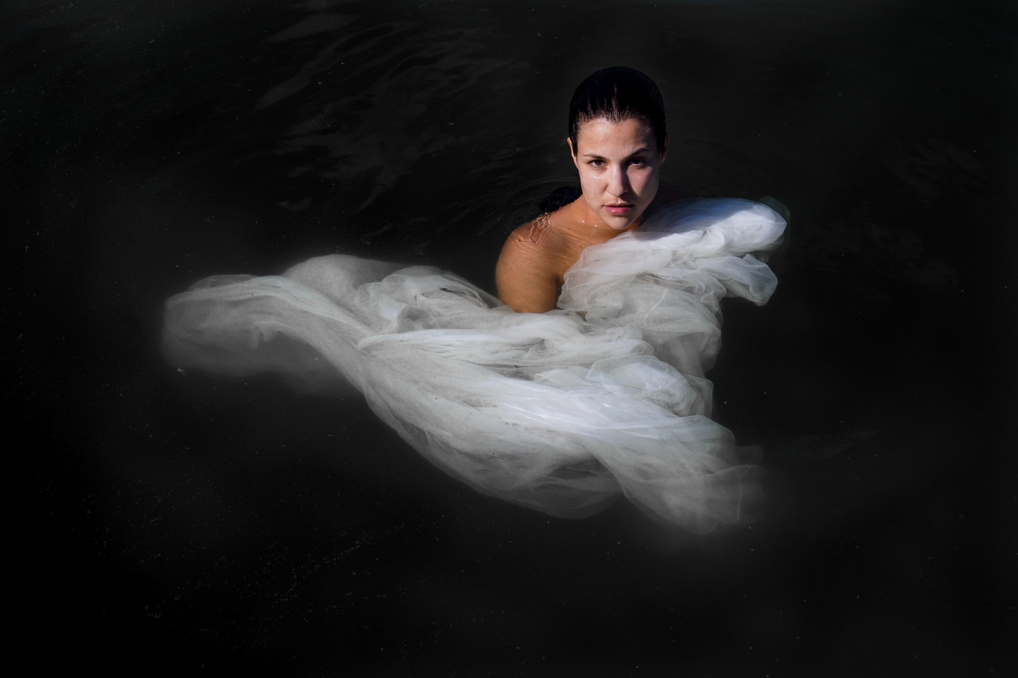 Eine Frau mit einem seidenen Wasserkleid bedeckt steht im Wasser.