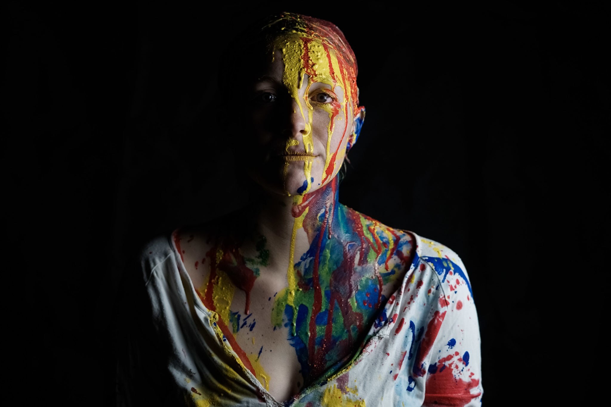 Gesicht einer Frau mit blauer, gelber und roter Farbe beschmiert. Aufnahme in wuerzbuger Umgebung in einem Studio fotografiert von Felicitas Jander. Sehen Sie mehr im gesamten Portfoliobeitrag.